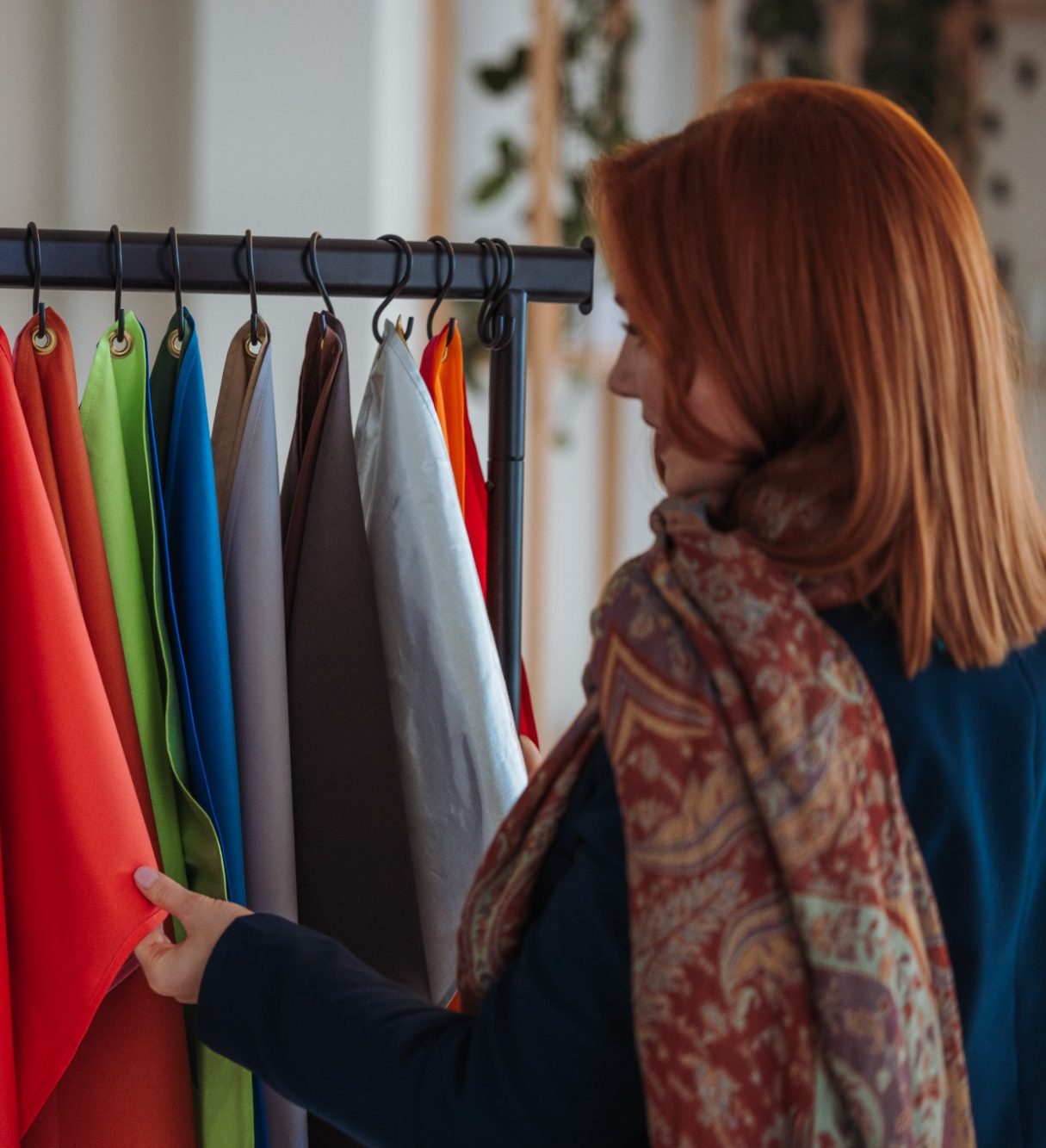 Julia Dosch - zertifizierte Holistic Colour & Style Professional Julia Dosch wählt Stoffe für die Farbberatung von einem Regal aus.